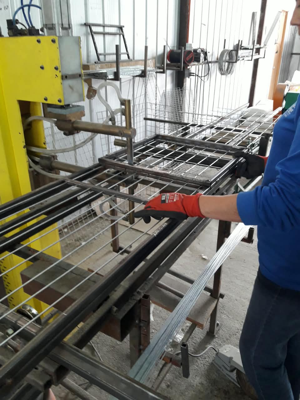 Maestro soldando la estructura de alambre de una jaula